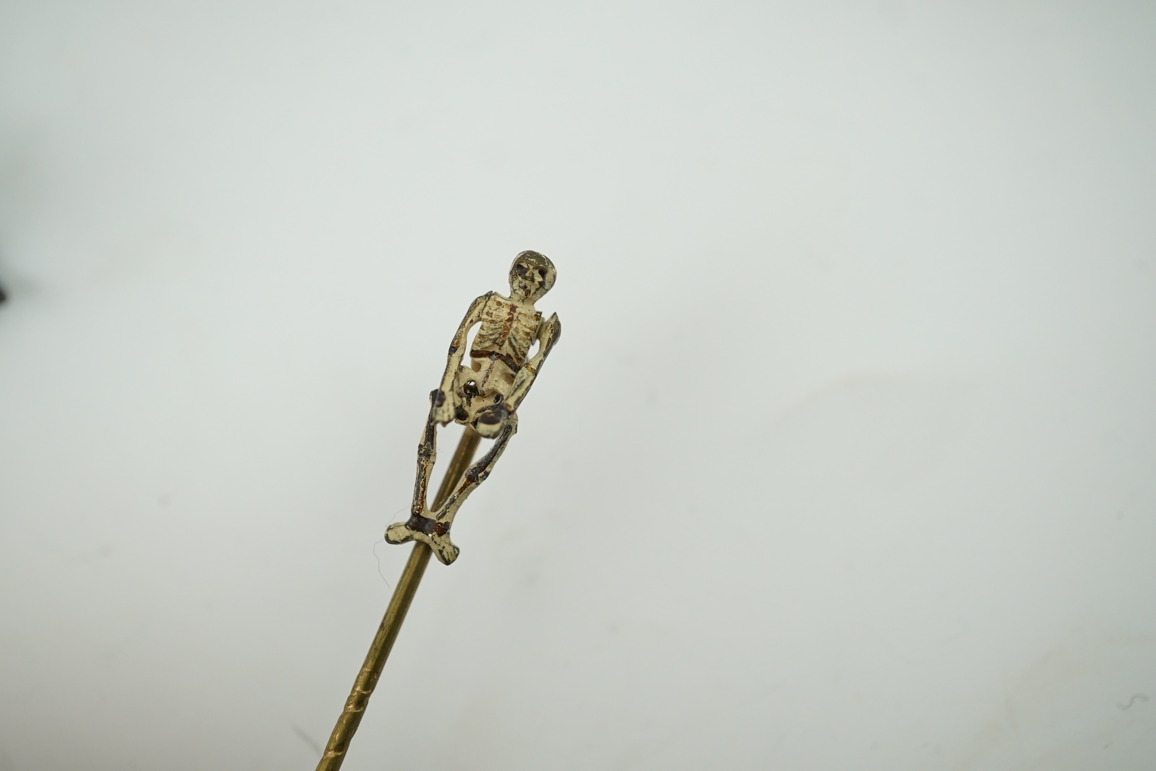 Four novelty miniature cold painted bronzes; black boy with cradle, black baby, cat and pig and a similar articulated arm skeleton stickpin,7cm long. Condition - some chipping to paint